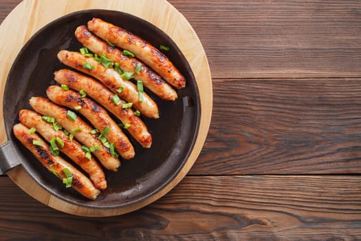 Delicious sausages cooked in a frying pan on a wooden table. copy space.