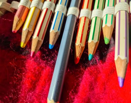 Selective focus close up at color pens lying on a red felt surface