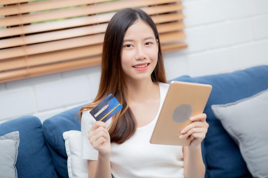 Young asian woman smiling holding credit card shopping online with tablet computer buying and payment, girl using debit card purchase or transaction of finance, lifestyle and e-commerce concept.