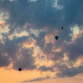 three hot air balloons in colorful sky with clouds during sunrise