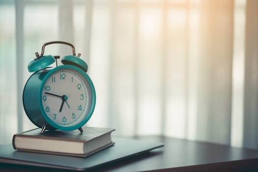 An alarm clock on a diary notebook and laptop for the concept of work, study and time management.