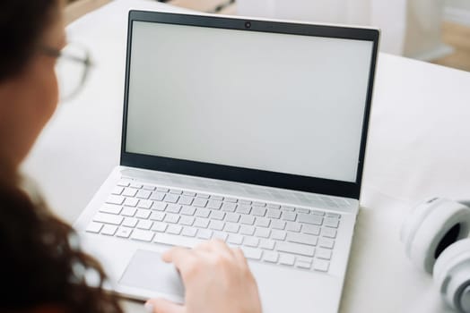 Over shoulder view of woman student elearning looking at white mock up blank screen using laptop computer learning online, remote working concept. Website mockup display template for ads concept