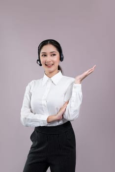 Asian female call center operator with smile face advertises job opportunity, wearing a formal suit and headset holding hand gesture for product on customizable isolated background. Enthusiastic