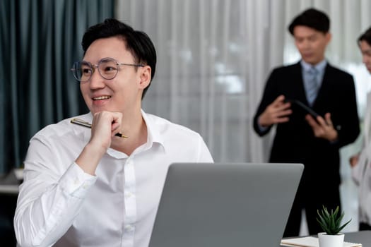 Portrait of focus young successful confident male manager, executive wearing business wear in harmony office arm crossed with blurred meeting background of colleagues, office worker.