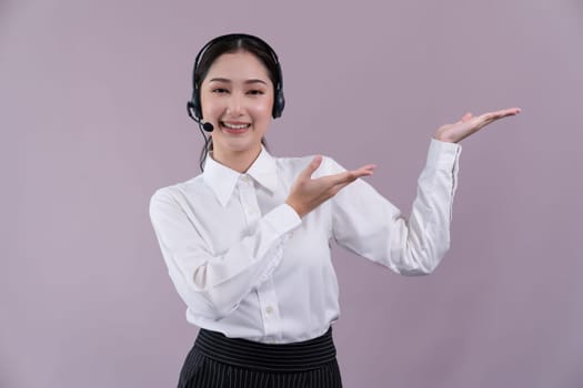 Asian female call center operator with smile face advertises job opportunity, wearing a formal suit and headset holding hand gesture for product on customizable isolated background. Enthusiastic