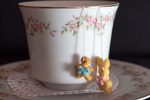 close-up of a porcelain tea cup with the detail of two small sweets hanging from a thread. High quality photo
