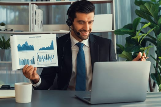 Business man wearing headphone present financial data or BI paper via laptop during online meeting. Remote work concept with virtual meeting presentation of effectiveness remote work. Fervent