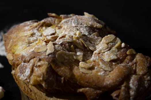 close-up of a cake with almonds on top and icing sugar on a black background. High quality photo