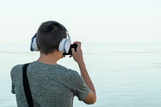 a young man takes pictures on his phone on the seashore. photo