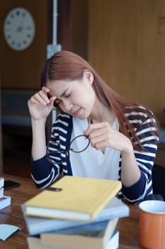 A portrait of an Asian teenage girl showing headaches and discouragement from studying in the library.