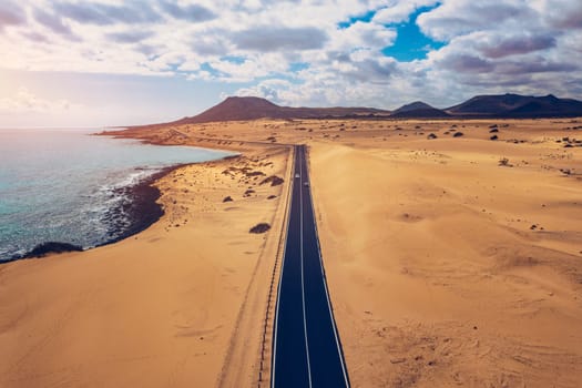 Fuerteventura, Corralejo sand dunes nature park. Beautiful Aerial Shot. Canary Islands, Spain. Aerial view of an empty road through the dunes at the sunset. Fuerteventura, Canary Islands, Spain.