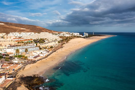 Aerial view of beach in Morro del Jable town (Morro Jable beach) on Fuerteventura island, Canary Islands, Spain. One of the best beach in the Canaries. Motorral lighthouse in distance.
