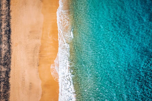Beach with turquoise water on Fuerteventura island, Spain, Canary islands. Aerial view of sand beach, ocean texture background, top down view of sea waves by drone. Fuerteventura, Spain.