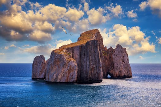 High cliffs of Mediterranean coast, "Pan di Zucchero" stack rock in Masua, west coast of Sardinia, Italy. Concali Su Terrainu with Porto Corallo on background. Sardinia island, Italy, Europe.