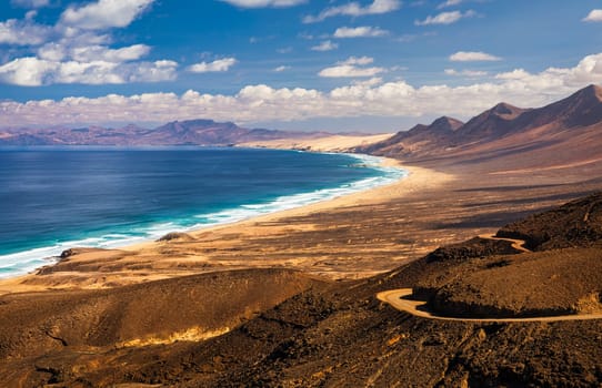 Amazing Cofete beach with endless horizon. Volcanic hills in the background and Atlantic Ocean. Cofete beach, Fuerteventura, Canary Islands, Spain. Playa de Cofete, Fuerteventura, Canary Islands.