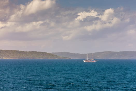 Sailboat in the sea in the evening sunlight with mountains background, luxury summer adventure, active vacation in Mediterranean sea, Croatia. Sailing ship luxury yacht with white sails in the Sea. 