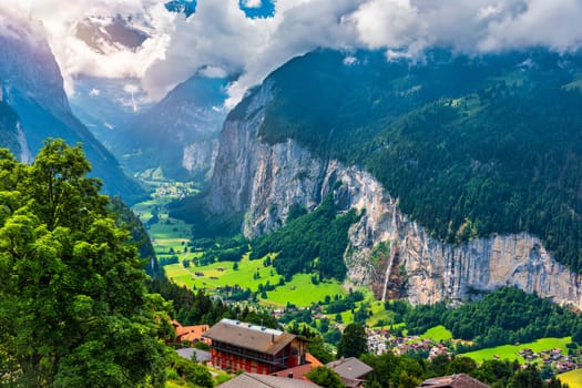 Amazing summer landscape of touristic alpine village Lauterbrunnen with famous church and Staubbach waterfall. Location: Lauterbrunnen village, Berner Oberland, Switzerland, Europe.