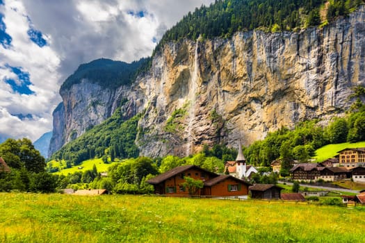 Lauterbrunnen valley with famous church and Staubbach waterfall. Lauterbrunnen village, Berner Oberland, Switzerland, Europe. Spectacular view of Lauterbrunnen valley in a sunny day, Switzerland.