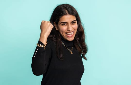 Happy joyful indian woman shouting, celebrating success, winning, birthday, lottery jackpot goal achievemen, good news, victory. Young hindu girl isolated on blue studio background