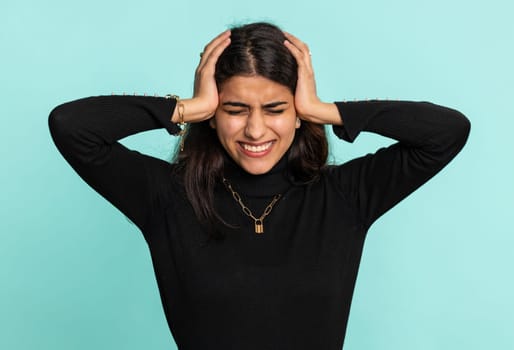 Dont want to hear and listen. Frustrated annoyed irritated indian woman covering ears gesturing No, avoiding advice ignoring unpleasant noise loud voices. Pretty hindu girl alone on blue background