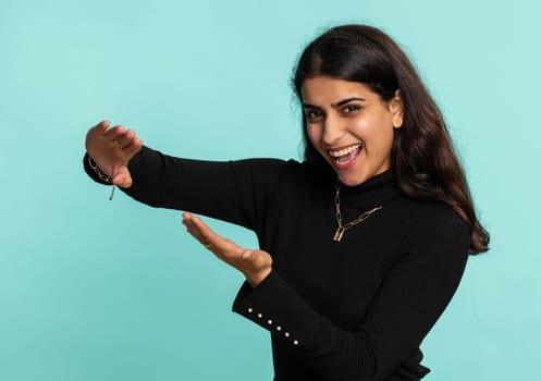 Young indian woman showing wasting, throwing money around, more tips, big profit, winning lottery jackpot, successful shopping payment purchase, cashback. Hindu girl isolated on studio blue background