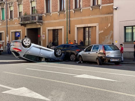 Cremona, Italy - 18th April 2023 just rolled over crashed car after an accident, police officer helping with traffic