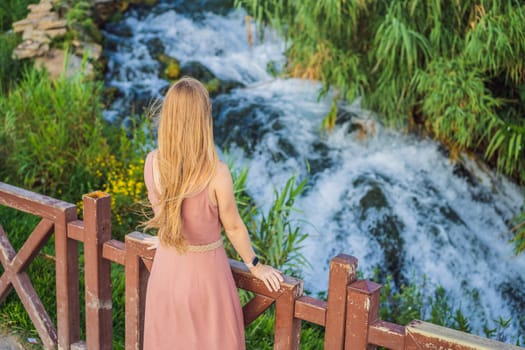 Beautiful woman with long hair on the background of Duden waterfall in Antalya. Famous places of Turkey. Lower Duden Falls drop off a rocky cliff falling from about 40 m into the Mediterranean Sea in amazing water clouds. Tourism and travel destination photo in Antalya, Turkey. Turkiye.