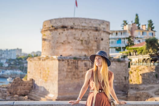 Woman tourist on background of Hidirlik Tower in Antalya against the backdrop of the Mediterranean bay of the ancient Kaleici district, Turkey. Turkiye.