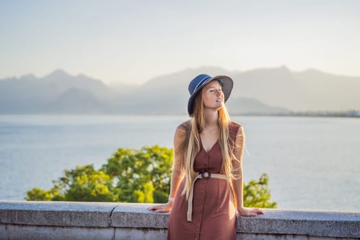 Happy woman tourist on background of Antalya sea and mountain views, sea in Turkey Antalya City. female tourist traveler discover interesting places and popular attractions and walks in the old city Kalechi of Antalya, Turkey. Turkiye.
