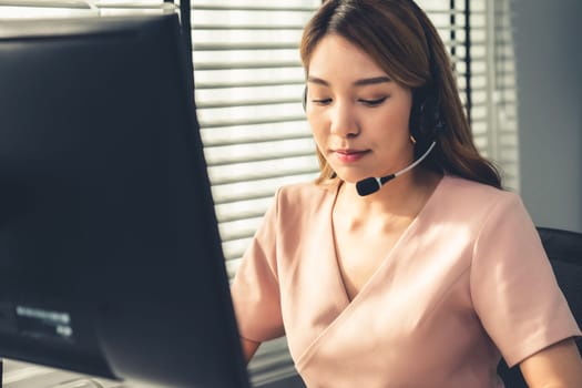 Competent female operator working on computer and while talking with clients. Concept relevant to both call centers and customer service offices.