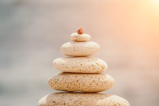 Pyramid stones on the seashore with warm sunset on the sea background. Happy holidays. Pebble beach, calm sea, travel destination. Concept of happy vacation on the sea, meditation, spa, calmness.