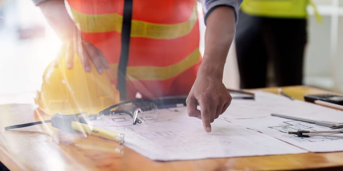 Architect and Engineer working with blueprints for architectural plan, engineer sketching a construction project, green energy concept.