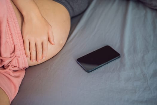 Pregnant girl with a smartphone. The concept of a negative impact on the unborn child in the womb. Violation of the nervous system of the child, reproductive.