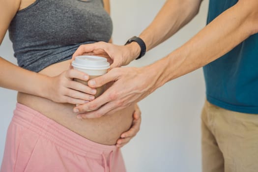 Husband forbids pregnant wife to drink coffee. A pregnant woman holds a cup of coffee in her hands. Caffeine safety, myths about coffee during pregnancy concept.