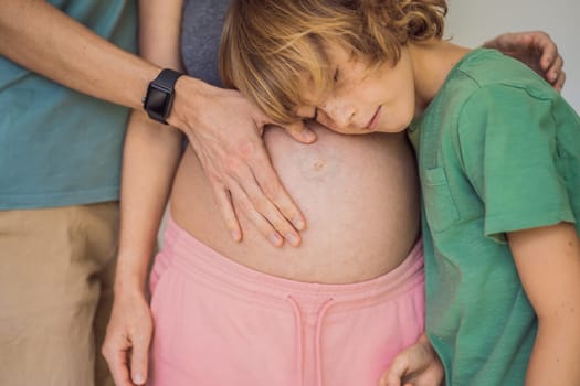 Mother's day, father's day, little cute blond boy touching mom's pregnant belly, husband holding his wife by the belly.