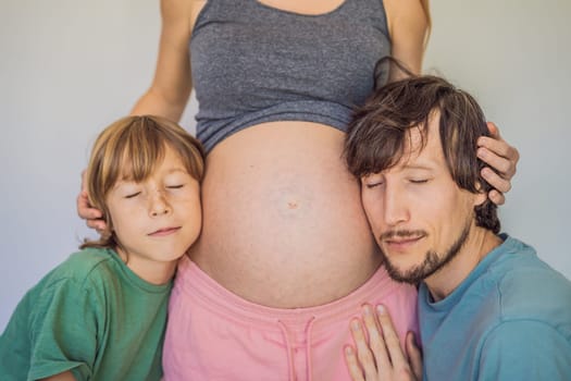 Father and elder son listen to mom's pregnant belly.