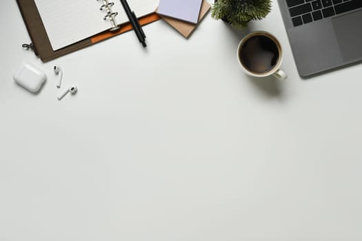 Modern white office desk table with laptop computer, cup of coffee and notebook. Top view with copy space, flat lay