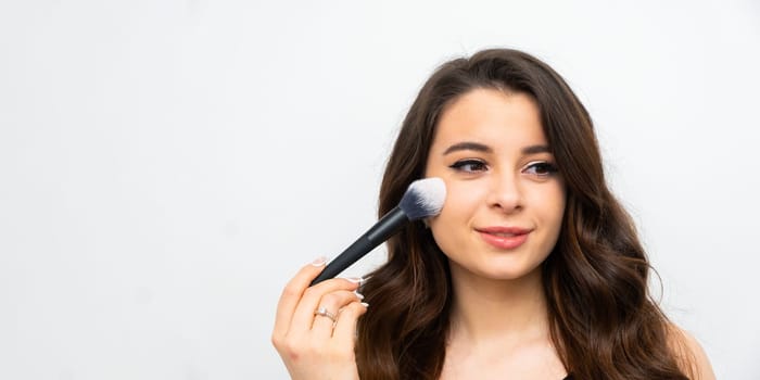 Young happy smiling woman applying contouring or blush on cheeks with big brush.