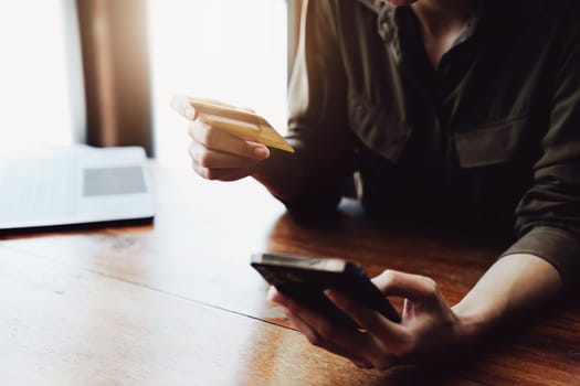 Portrait of young Asian woman using credit card and phone for online shopping.