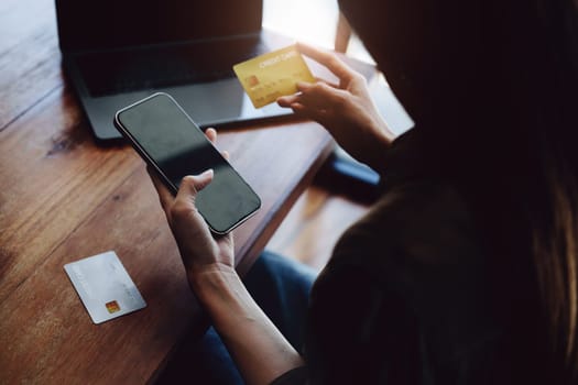 Portrait of young Asian woman using credit card and phone for online shopping.