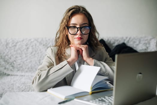 Young serious busy professional businesswoman employee or student wearing glasses using a laptop watching online webinars or training web courses, looking at computers, thinking, and doing research