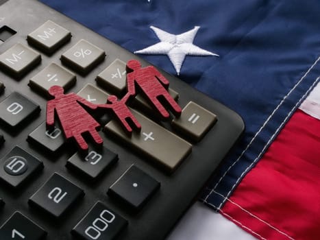 USA flag, a calculator and family figurines. Child tax credit concept.