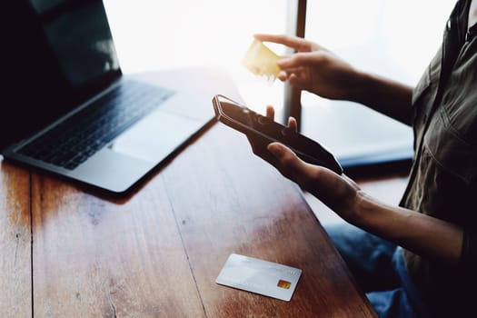 Portrait of young Asian woman using credit card and phone for online shopping.