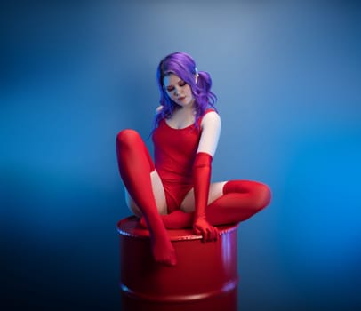 sexy girl in a red bodysuit, stockings and red gloves poses erotically on a blue background of copy paste