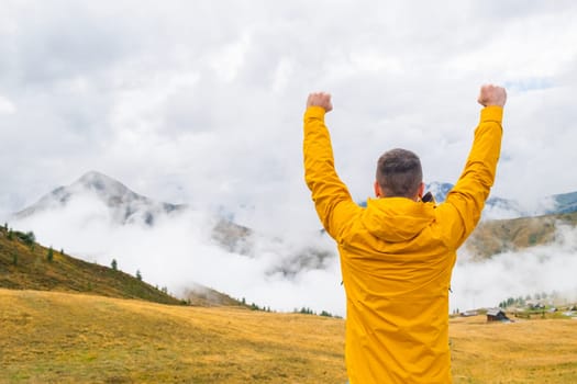 Happy man spreads hands and enjoy amazing view of Italian Alps in dense fog.