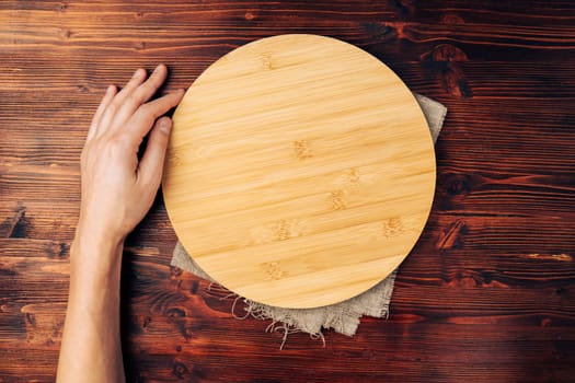 Empty round kitchen board on a wooden background, an empty copy space