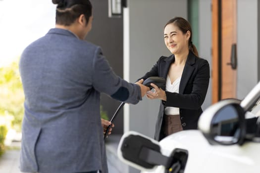 Concept of a progressive young couple with home charging station for an electric vehicle, encouraging healthy and clean environment. Electric vehicle powered by sustainable, clean energy technology.