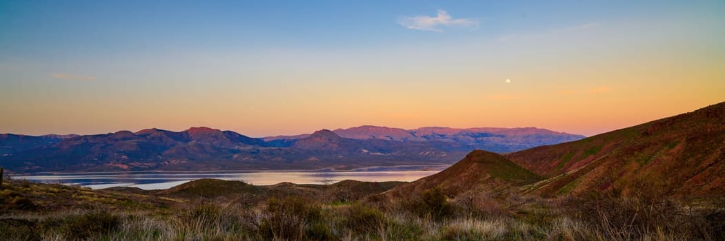 Evening view of Roosevelt Lake with full moon rising in the sky.