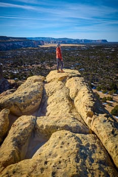 Woman stand at the edge of the sandstone cliffs surveying ancient lava flows at El Mapais National Monument, New Mexico.