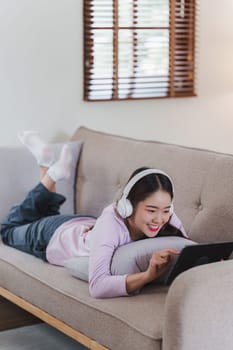 Attractive Asian woman resting comfortable living room and using digital tablet, Relax, Sofa, Lifestyle.